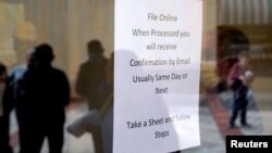 People who lost their jobs are reflected in the door of an Arkansas Workforce Center as they wait in line to file for unemployment following an outbreak of the coronavirus disease (COVID-19), in Fort Smith, Arkansas.