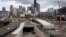 A portion of a new offramp, center right, for Highway 99, stands completed and adjacent to the entrance for northbound traffic into the tunnel being constructed in Seattle. The offramp has a new type of column that flexes when the ground shakes in an earthquake, then snaps back to its original position.
