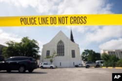 Police tape surrounds the parking lot behind the Emanuel AME Church as FBI forensic experts work the crime scene, June 19, 2015.