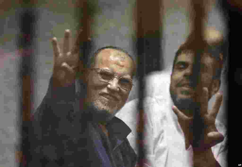 Senior Muslim brotherhood leader Essam el-Erian (left) flashes the four-fingered symbol in support of former Egyptian president Mohamed Morsi. Morsi was sentenced to 20 years by a Cairo court, April 21, 2015.