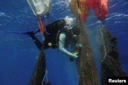 A volunteer diver of the environmental group Aegean Rebreath uses balloons to lift ghost nets from the bottom of the sea, off the island of Salamina, Greece, June 30, 2019. Picture taken June 30, 2019. REUTERS/Stelios Misinas