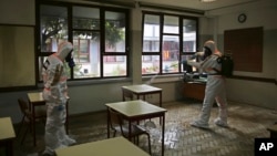 Petugas menyemprotkan cairan disinfektan di sebuah ruangan kelas di Lisbon,Portugal, di tengah pandemi Covid-19, 29 Apri 2020. (Foto: dok). Portugal bersiap-siap menutup semua sekolah mulai dari TK hingga universitas mulai hari Jumat untuk menangani lonjakan tajam kasus Covid-19.