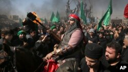 A Shiite re-enacts the events of Ashoura while Iranian and Iraqi Shiite Muslims mourn in a procession in southern Tehran, Iran on Oct. 12, 2016. 