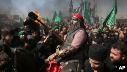 FILE- A Shiite re-enacts events of Ashoura as Iranian and Iraqi Shiite Muslims mourn in a procession in Tehran, Iran, Oct. 12, 2016. Shiites mark Ashoura, the tenth day of the Muslim month of Muharram, to commemorate the martyrdom of Imam Hussein, a grandson of Prophet Muhammad.