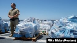 Direktur operasi udara untuk Bea Cukai dan Perlindungan Perbatasan AS Jeremy Battenfield berdiri di samping 13 ton kokain yang disita di lepas pantai Meksiko dan Amerika Selatan Tengah di sebuah pelabuhan di San Diego, California, AS, 26 Juli 2019.