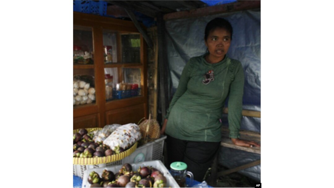 Jumilah lost five cattle from the volcanic eruption of Mount Merapi. She is slowly rebuilding her life by selling fruits at a roadside stall.