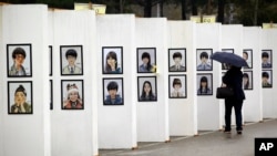 A woman looks at caricatures of the victims of the sunken ferry Sewol outside a group memorial altar in Ansan, South Korea, Thursday, April 16, 2015.