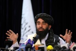 In front of a Taliban flag, Taliban spokesman Zabihullah Mujahid speaks at at his first news conference, in Kabul, Afghanistan, Tuesday, Aug. 17, 2021. (AP Photo/Rahmat Gul)