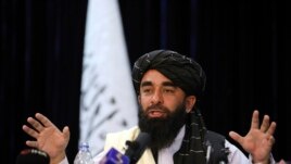 In front of a Taliban flag, Taliban spokesman Zabihullah Mujahid speaks at at his first news conference, in Kabul, Afghanistan, Tuesday, Aug. 17, 2021. (AP Photo/Rahmat Gul)