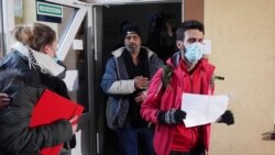 Syrian migrant Masour, center, and Iraqi migrant Hama, right, are brought out of the hospital by a border guard in Bielsk Podlaski, Poland, Nov. 19, 2021, after crossing from Belarus.