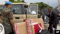 FILE - Watched by a Uruguayan peacekeepers (L) a 19-year-old man (R) who claims he was sexually abused by other Uruguayan peacekeepers, picks up his luggage from a vehicle upon his arrival to Toussaint Louverture airport, Haiti, May 8, 2012. 