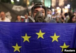 Seorang demonstran memegang bendera Uni Eropa saat protes terhadap RUU tentang "agen asing" di Tbilisi, Georgia, 1 Mei 2024. (Foto: REUTERS/Irakli Gedenidze)