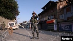 Seorang petugas keamanan India berjaga di jalan sepi di Srinagar, selama pembatasan pasca pembatalan status khusus untuk Kashmir oleh pemerintah India, 23 Agustus 2019. (REUTERS / Danish Ismail)