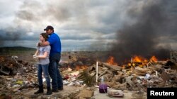 Michael Stanek hugs his daughter Kennedy Stanek as they take a break from helping friends sift though the rubble of their homes in Vilonia, Arkansas, April 30, 2014.