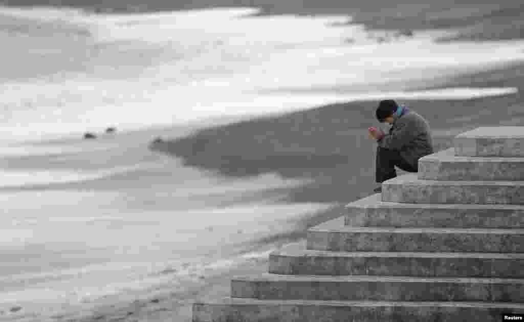 A woman faces the sea to pray while mourning the victims of the March 11, 2011 earthquake and tsunami disaster, in Iwaki, Fukushima prefecture, Japan.