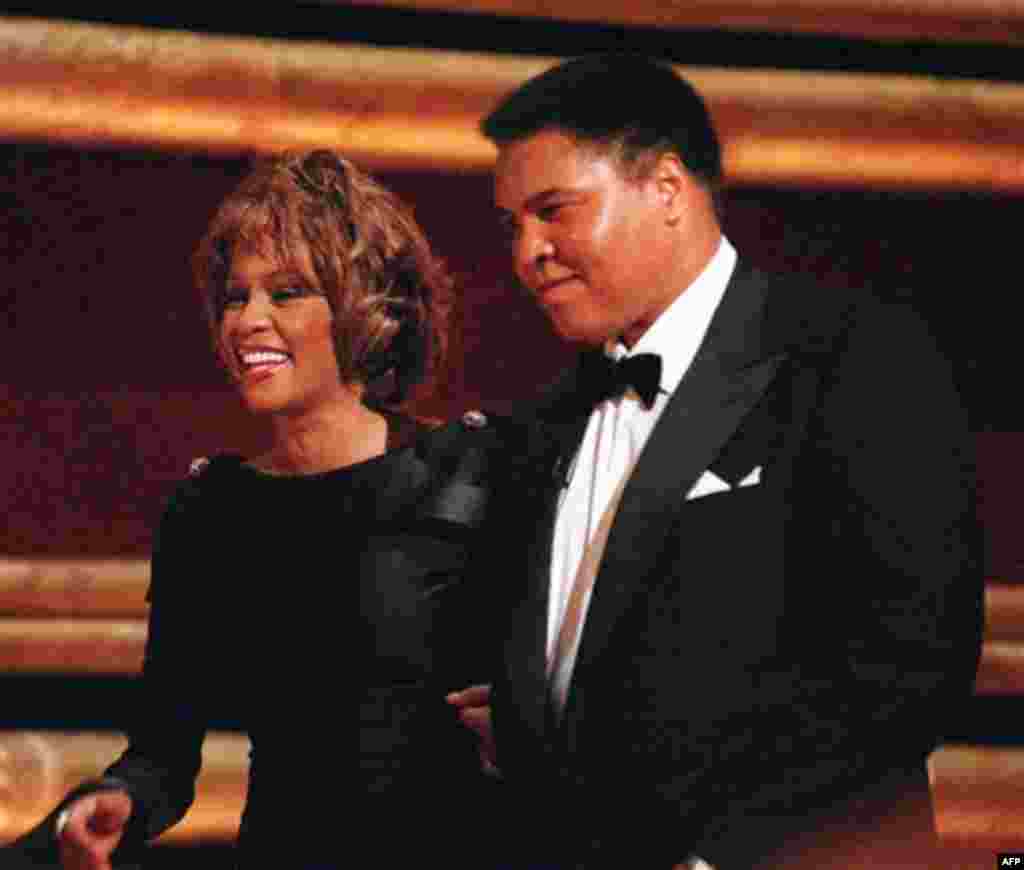 FILE - In this Oct. 21, 1998 file photo, former World Heavyweight Boxing Champion Muhammad Ali is greeted by singer Whitney Houston as he arrives on stage at New York's Radio City Music Hall to accept a GQ "Men of the Year" Award. Whitney Houston, who rei