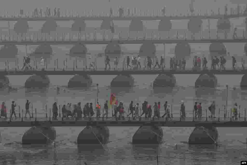 Hindu pilgrims carrying their belongings walk over floating pontoon bridges to go to Sangam, the confluence of the Ganges, Yamuna and mythical Saraswati rivers, to take part in the Maha Kumbh Mela festival in Prayagraj, India.