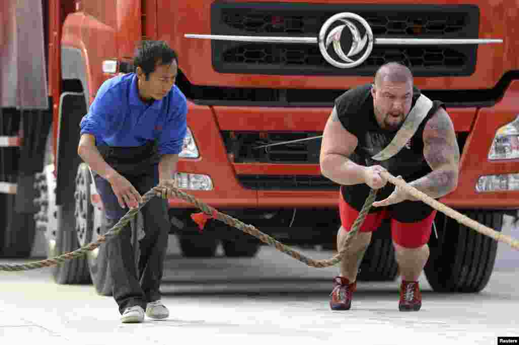British participant Kenneth Nowicki (R) drags a truck during the annual Chinese Hercules Open in Xiangyang, Hubei province, China. 