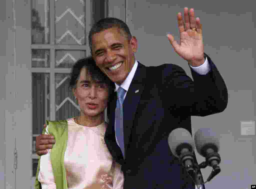 U.S. President Barack Obama waves to the media as he embraces Burmese opposition leader Aung San Suu Kyi after they spoke to the media at her residence in Rangoon, November 19, 2012.
