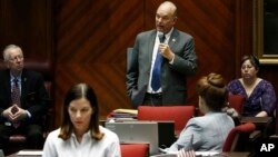 Arizona Rep. Michelle Ugenti-Rita, foreground, and others listen to Rep. Don Shooter, center background, as he reads a statement regarding sexual harassment and other misconduct complaints made against him by Ugenti-Rita and others, on the House floor at the Capitol, Jan. 9, 2018, in Phoenix, Arizona.