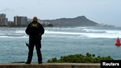 Honolulu police officer Chad Asuncion monitors the water conditions and warns surfers about the conditions as Hurricane Lane approaches Honolulu, Hawaii, Aug. 23, 2018.
