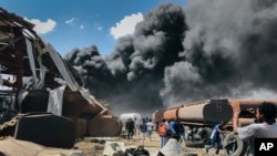 FILE - People are seen in front of clouds of black smoke from fires in the aftermath at the scene of an airstrike in Mekele, the capital of the Tigray region of northern Ethiopia. Taken 10.20.2021