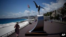 A woman walks along Nice's Promenade des Anglais next to the "L'Ange de la Baie" statue created by Jean-Marie Fondacaro, to commemorate the 2016 terror attack, in Nice, South of France, Sept. 4, 2022.