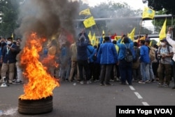 Demonstran membakar keranda di dekat pagar kawat berduri yang dipasang aparat keamanan, dalam aksi unjuk rasa di Patung Kuda, Medan Merdeka Barat, Jakarta, (5/9). (VOA/Indra Yoga)