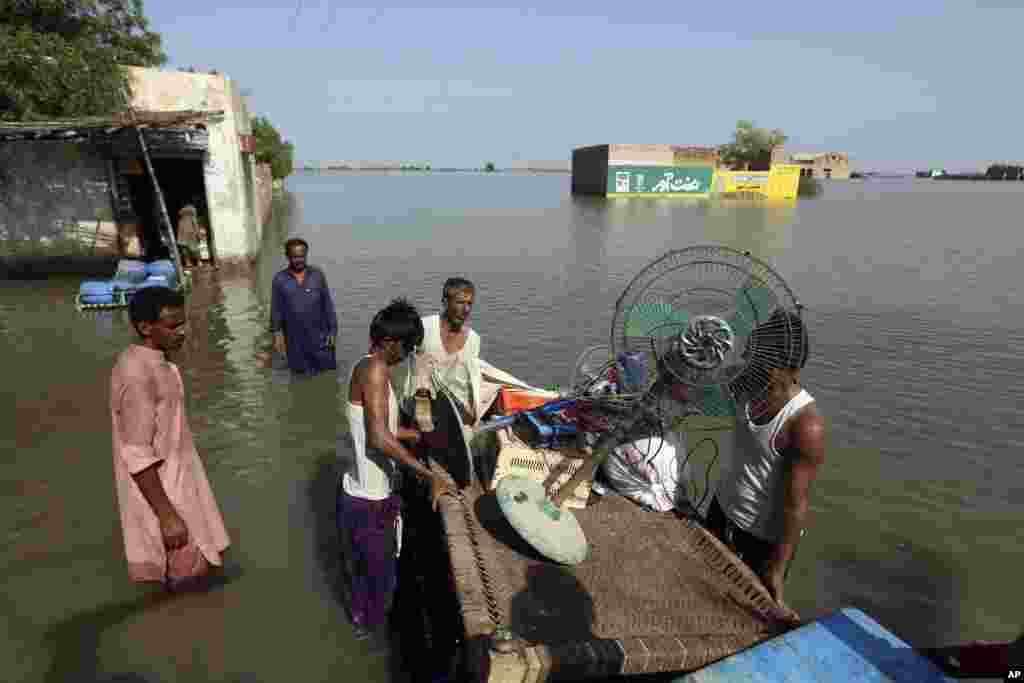 People use a cot to salvage belongings from their nearby flooded home, in Jaffarabad, Pakistan, Sept. 5, 2022. 