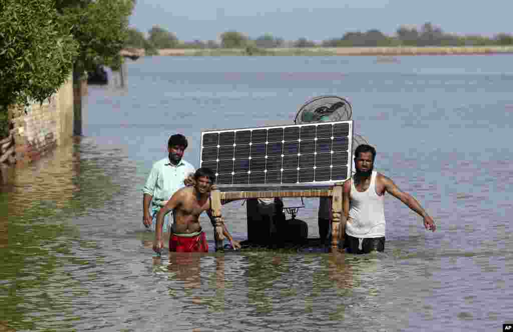 Victims of unprecedented flooding from monsoon rains use a cot to salvage belongings from their flooded home, in Jaffarabad, Pakistan.