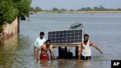Victims of unprecedented flooding from monsoon rains use a cot to salvage belongings from their flooded home, in Jaffarabad, Pakistan, Sept. 5, 2022.