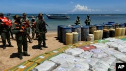 Sacks containing illegal drugs and plastic barrels containing fuel, seized by the armed forces of Venezuela are displayed at a beachside campsite in the village of Tiraya, Venezuela, Sept. 5, 2022. 