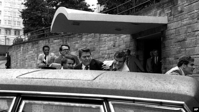FILE - In this March 30, 1981, photo, U.S. president Ronald Reagan, center, is shown being shoved into his limousine by secret service agents after being shot outside a Washington hotel. The man who shot Reagan is scheduled to leave a Washington mental ho
