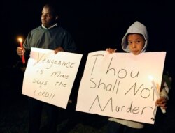Darick Lane dan putranya Desmond Lane memegang lilin di luar penjara sebelum eksekusi John Allen Muhammad di Pusat Pemasyarakatan Greensville di Jarratt, Virginia, 10 November 2009. (Foto: REUTERS/Jonathan Ernst)