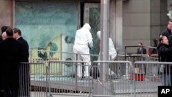 FILE - NYPD bomb squad unit inspects damage done by an explosive at military recruitment center in Times Square, March 6, 2008.