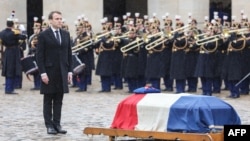 Presiden Prancis Emmanuel Macron (kiri) berdiri di dekat peti jenazah Letnan Kolonel Arnaud Beltrame, setelah secara anumerta memberinya penghargaan berupa "medal of Commander" di Legion of Honor Order dalam upacara nasional di Hotel des Invalides, Paris, 28 Maret 2018.