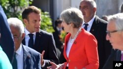 FILE - French President Emmanuel Macron (L) talks with British Prime Minister Theresa May when arriving for a family photo at the informal EU summit in Salzburg, Austria, Sept. 20, 2018. 