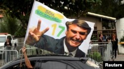 A supporter of Brazil's new president-elect, Jair Bolsonaro, celebrates in front of Bolsonaro's condominium at Barra da Tijuca neighborhood in Rio de Janeiro, Brazil, Oct. 29, 2018. 
