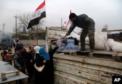 Shi'ite fighters of the Popular Mobilization Forces distribute food to the residents in a neighborhood recently liberated from Islamic State militants, on the eastern side of Mosul, Iraq, Jan. 15, 2017.