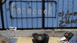 Opposition supporters rest near graffiti referring to Facebook in Tahrir Square in Cairo on Saturday