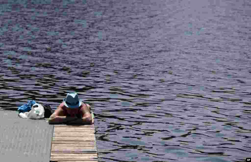 Seorang pria berjemur di tepi Danau Ada Ciganlija di Belgrade, Serbia. Cuaca panas telah tiba di Belgrade dengan suhu mencapai 32 derajat Celsius.