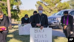 In this June 1, 2020, photo provided by the Catholic Diocese of El Paso, Bishop Mark Seitz, center, kneels with other demonstrators at Memorial Park holding a Black Lives Matter sign in El Paso, Texas. (Fernie Ceniceros/Catholic Diocese of El Paso via AP)