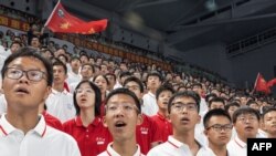 Students wave the national flag of China as they sing during the opening ceremony for undergraduates at the Wuhan University in Wuhan on Sept. 12, 2023.