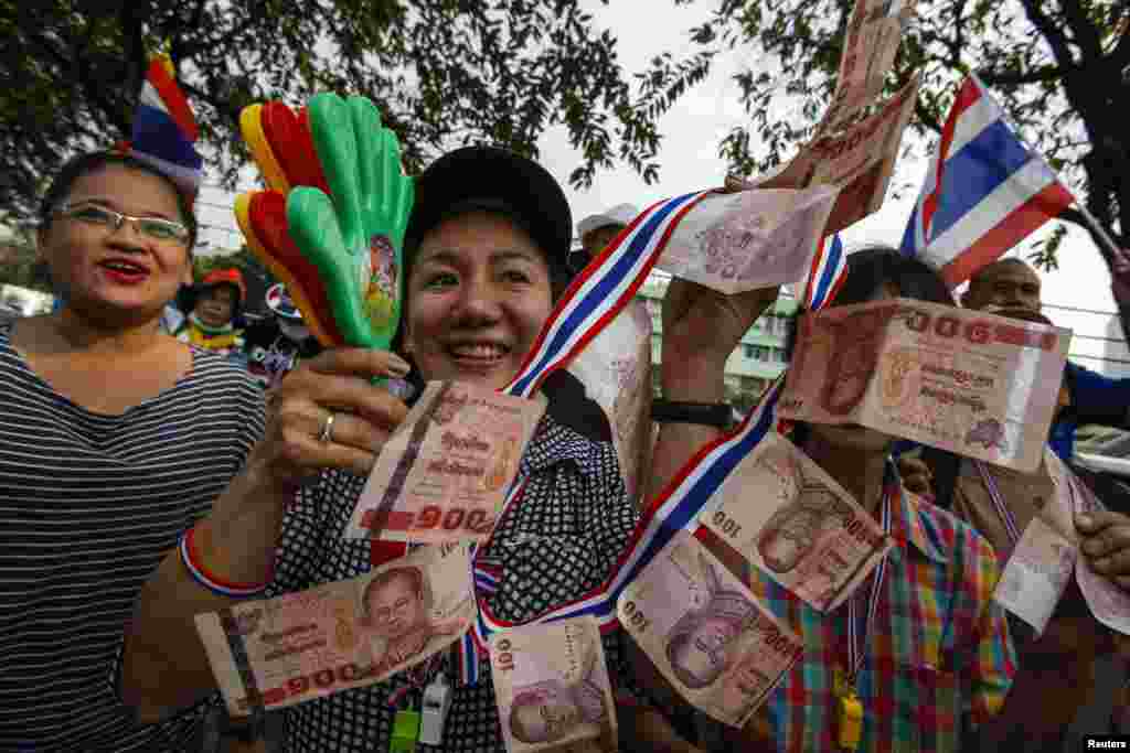 Anti-government protesters hold up Thai banknotes to donate to anti-government protest leader Suthep Thaugsuban during a rally in Bangkok, Jan. 7, 2014.