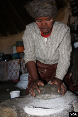 A woman grinds corn to make traditional beer in South Africa's Eastern Cape Province. (D. Taylor/VOA)