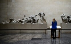 FILE - A woman looks at the Parthenon Marbles, a collection of stone objects, inscriptions and sculptures, also known as the Elgin Marbles, on show at the British Museum in London, Oct. 16, 2014.