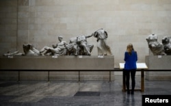 FILE - A woman looks at the Parthenon Marbles, a collection of stone objects, inscriptions and sculptures, also known as the Elgin Marbles, on show at the British Museum in London, Oct. 16, 2014.