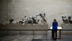 FILE - A woman looks at the Parthenon Marbles, a collection of stone objects, inscriptions and sculptures, also known as the Elgin Marbles, on show at the British Museum in London, Oct. 16, 2014.