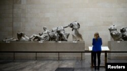 FILE - A woman looks at the Parthenon Marbles, a collection of stone objects, inscriptions and sculptures, also known as the Elgin Marbles, on show at the British Museum in London. Taken Oct. 16, 2014.