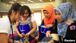 Para pembeli memperhatikan demonstrasi penggunaan ponsel Galaxy baru mereka oleh pegawai Samsung di Jakarta (11/4). (Reuters/Beawiharta) 